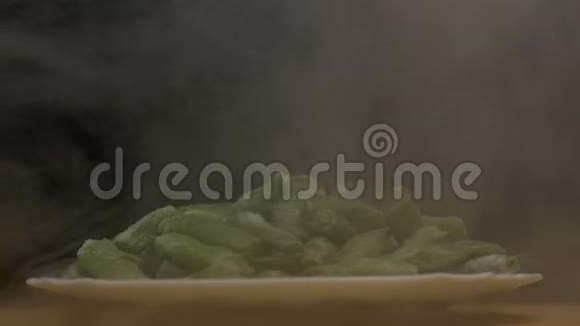 新鲜冷冻芦笋豆荚在黑色的背景下吹出凉爽和新鲜烟雾特写慢动作视频的预览图