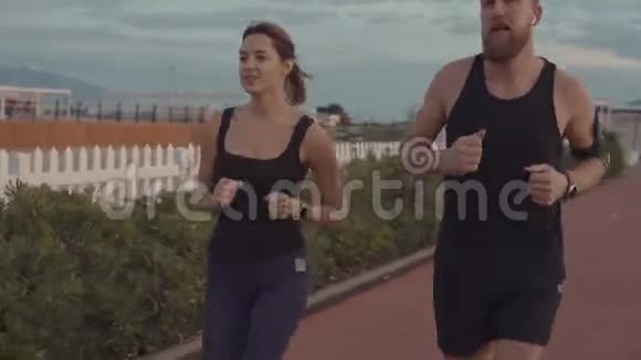 快乐的男女慢跑者正在清晨的城市堤上移动视频的预览图