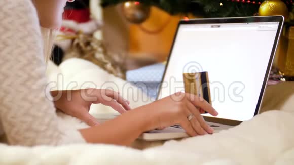 年轻女子为圣诞节在网上购物的4K视频她拿着信用卡用笔记本电脑视频的预览图