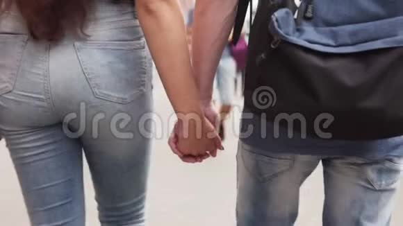年轻一对情侣牵着手一起走在城市大街上视频的预览图
