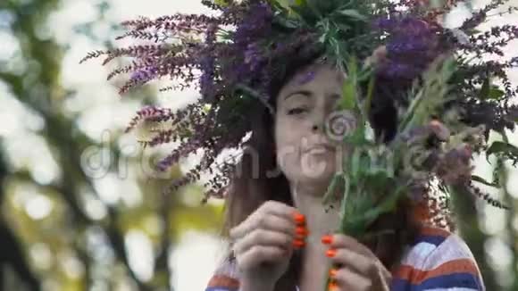 特写镜头美丽的女孩她的头上有一个来自矢车菊的花手里拿着一束田野花视频的预览图