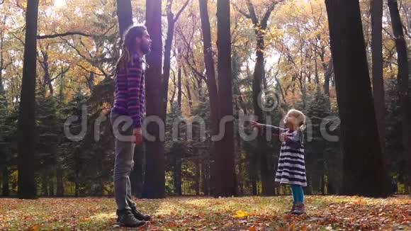 爸爸和女儿正在秋天的森林里玩耍爸爸抓住了孩子视频的预览图