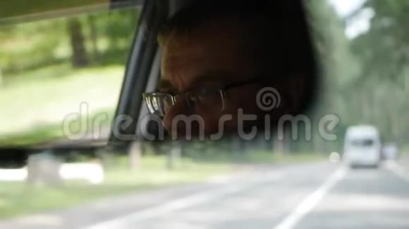 老人在乡间路开车汽车后视镜中的面部反射特写视频的预览图