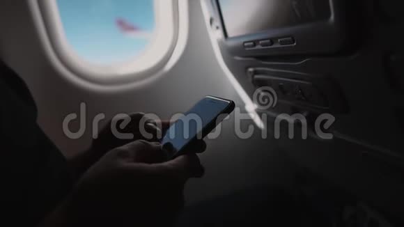 飞机机舱内男性手在手机屏幕上打字的特写镜头视频的预览图