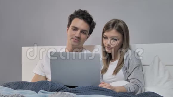 快乐青年夫妇在床上上网聊天视频的预览图