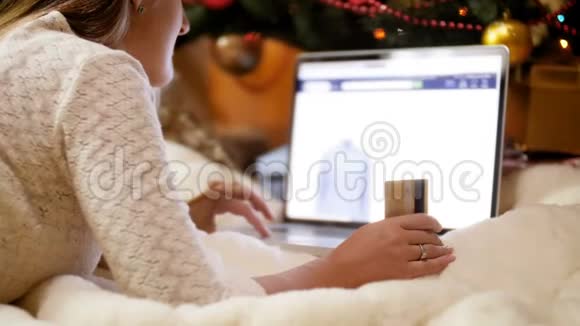 在网上商店用笔记本电脑买礼物和圣诞礼物的年轻女子4K镜头视频的预览图