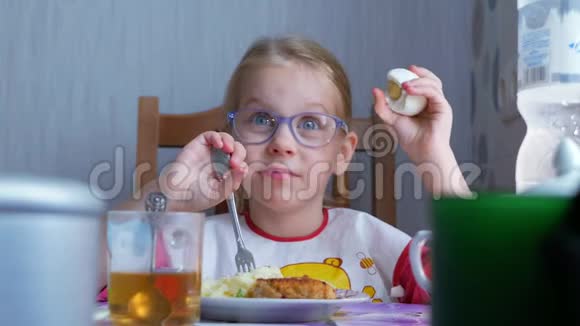 小可爱的小女孩在厨房的桌子上吃一个煮鸡蛋视频的预览图