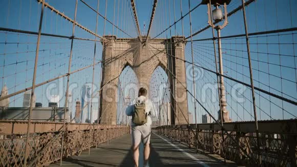 快乐的男性游客离开相机后景在阳光明媚的4K天沿着纽约布鲁克林大桥环顾四周视频的预览图