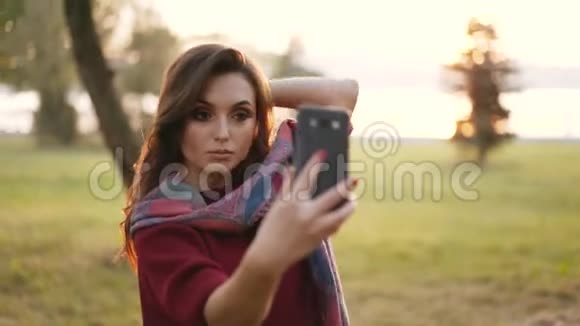 在秋天公园的智能手机上梳头的嬉戏女孩视频的预览图