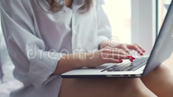 女人在窗台上的笔记本电脑上打字视频的预览图