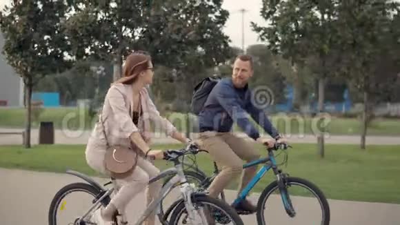 快乐的男女骑自行车的人在城市公园散步时愉快地聊天视频的预览图