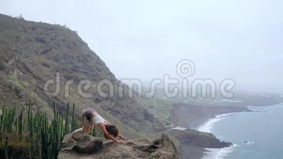 一位年轻的高加索女人在户外摆姿势一位坐在悬崖边上的女人姿势是视频的预览图