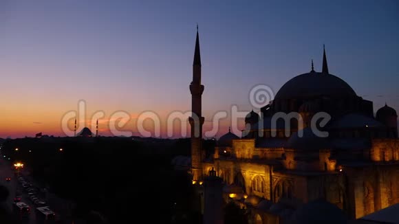 日落后的蓝色清真寺在一条有车辆的道路旁点亮视频的预览图