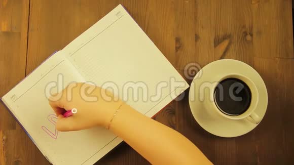 女孩在日记里用粉红色的记号笔写爱的词喝咖啡视频的预览图