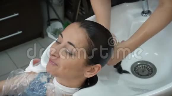 发型师洗完头后头发从水里挤出来用毛巾把头裹起来视频的预览图