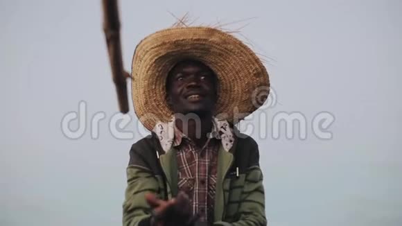 非洲青年男子坐在草帽里坐在船上说话的肖像用手展示视频的预览图