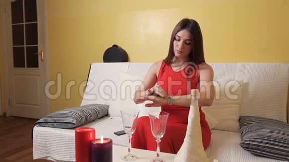 一个穿着红色裙子的年轻女孩准备了蜡烛眼镜准备了浪漫的晚餐等待她的丈夫很浪漫晚餐视频的预览图