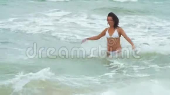 美丽的女人穿着白色的泳衣在暴风雨的时候在大海的波涛中嬉戏视频的预览图