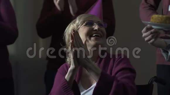 微笑的祖母在她70岁的生日聚会上拍手家庭传统视频的预览图