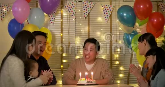 快乐的亚洲男性坐在桌子旁用蛋糕庆祝他的生日视频的预览图