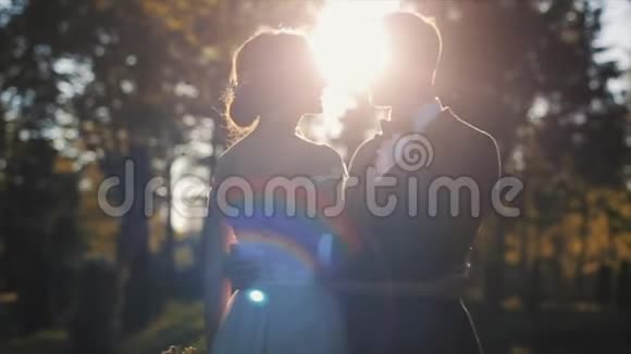 快乐的新娘和新郎站在秋天的公园里笑吻视频的预览图