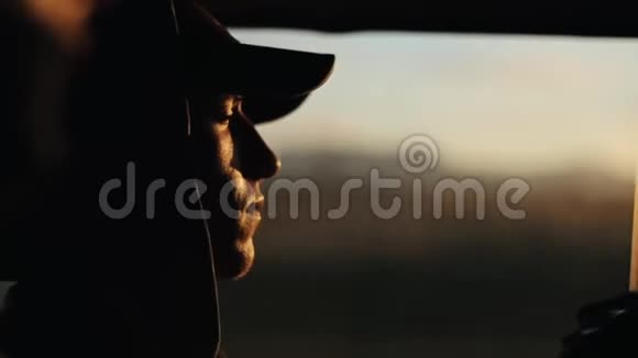 年轻的英俊男子坐在靠近窗户的移动汽车和思考休息闭上眼睛日落视频的预览图