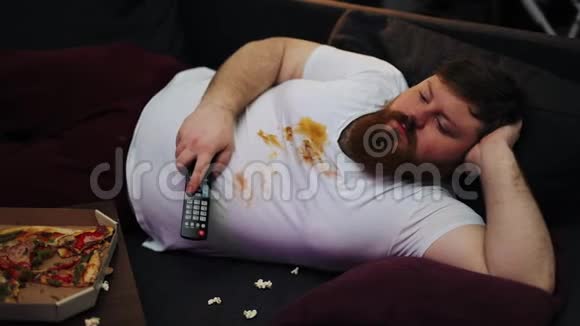 穿脏T恤的胖子笑着看客厅沙发上的电视机视频的预览图