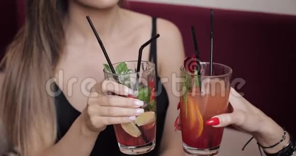 特写两个迷人的女性朋友的clink眼镜配上新鲜的鸡尾酒和一起喝酒视频的预览图