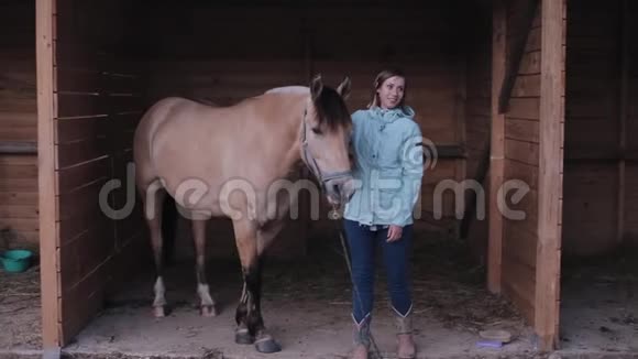 一位美丽的女骑手站在一匹整齐的马旁边把它拖住并与它交谈视频的预览图