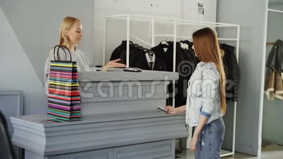 开朗的顾客是用信用卡支付购买的衣服同时站在出纳办公桌店员视频的预览图