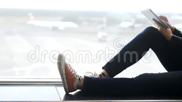 年轻女子手拿平板电脑坐在机场视频的预览图
