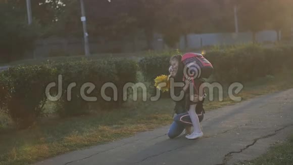 妈妈从学校遇到了她的小女儿穿着校服带着背包的女孩向她母亲跑去慢动作视频的预览图