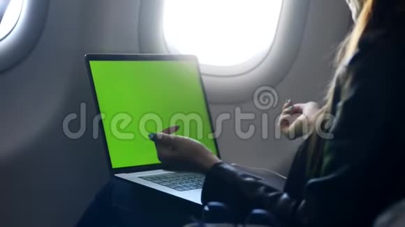 年轻女性使用笔记本电脑在飞机上发送电子邮件视频的预览图