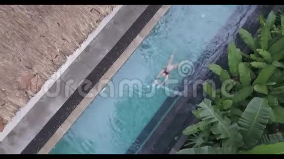 在热带酒店的露天游泳池里游泳的女孩令人印象深刻的鸟瞰图视频的预览图