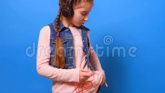 一个小女孩把耳机和电话连接起来享受音乐视频的预览图