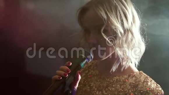 一位年轻女子在漆黑的烟雾弥漫的房间里唱歌的肖像视频的预览图