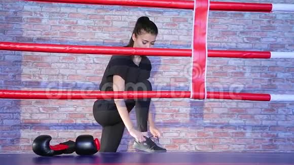 穿黑色运动服系鞋带运动鞋脚踩拳击圈戴拳击手套的深褐色女运动员视频的预览图