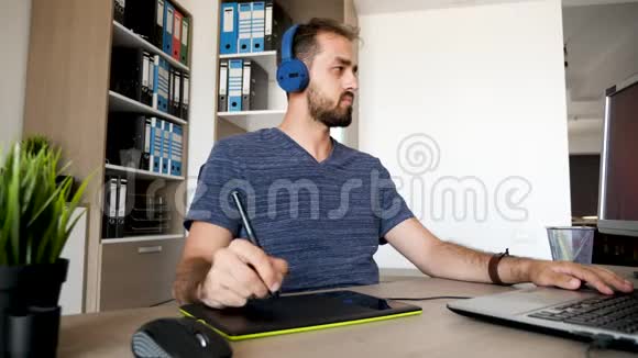 男人用耳机听音乐用数码平板电脑画画视频的预览图