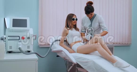 女士腿上的激光脱毛那个女孩躺在治疗室的医疗眼镜里的沙发上这就是视频的预览图