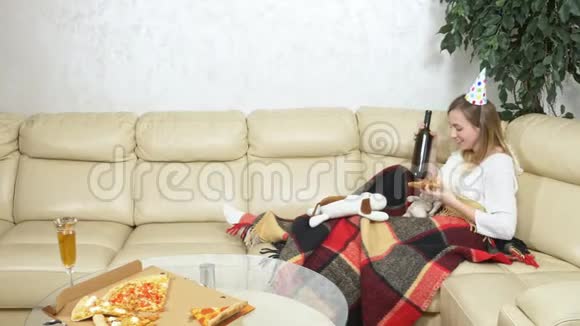 孤独的女人在软玩具的陪伴下在沙发上喝酒视频的预览图
