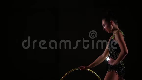 侧视苗条迷人的女运动员穿着鲜艳的泳装在艺术体操中站着抱箍呼吸沉重视频的预览图