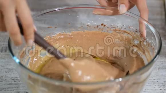 糖果师做面团一只手拿着塑料铲子把面团放在玻璃碗里烤巧克力视频的预览图