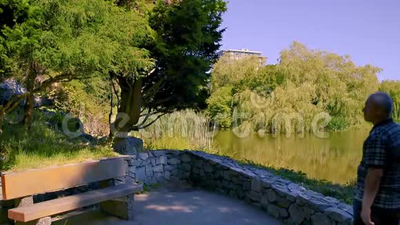 穿着衬衫的人走近公园的一条长凳坐在上面从长凳上站起来离开视频的预览图
