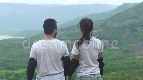 旅行夫妇男女拥抱在山边看着绿色的山谷和热带森林游客视频的预览图
