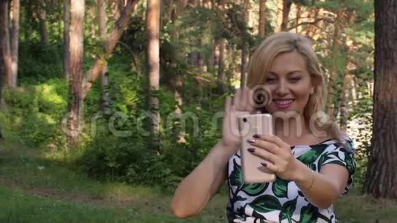 美丽的笑脸女人在公园里视频聊天视频的预览图
