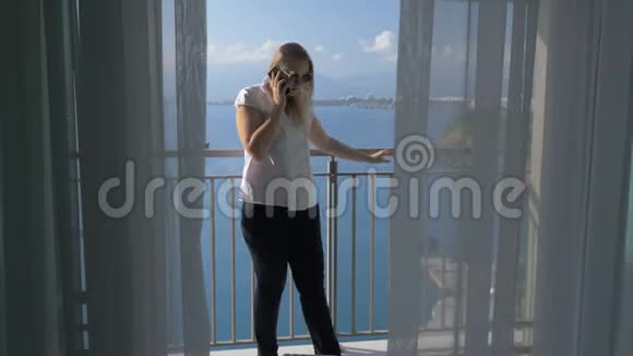 一个女人在酒店阳台上对着美丽的风景打电话视频的预览图