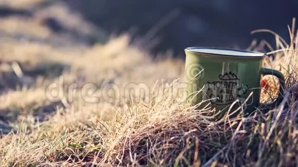 山上金色草地上装满热茶的杯子的特写镜头视频的预览图
