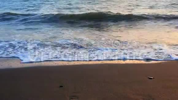 海浪翻滚上岸的特写低角度的视野慢镜头日出或日落时间视频的预览图