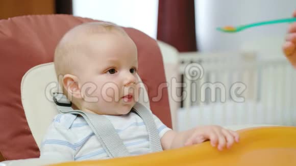 可爱的宝宝在家里的椅子上吃饭视频的预览图