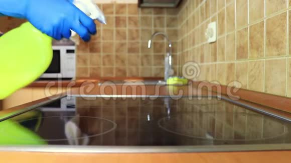 用除脂剂喷雾剂和一名戴黄色橡胶手套的妇女用吸尘器清洁厨房灶台烹饪面板视频的预览图